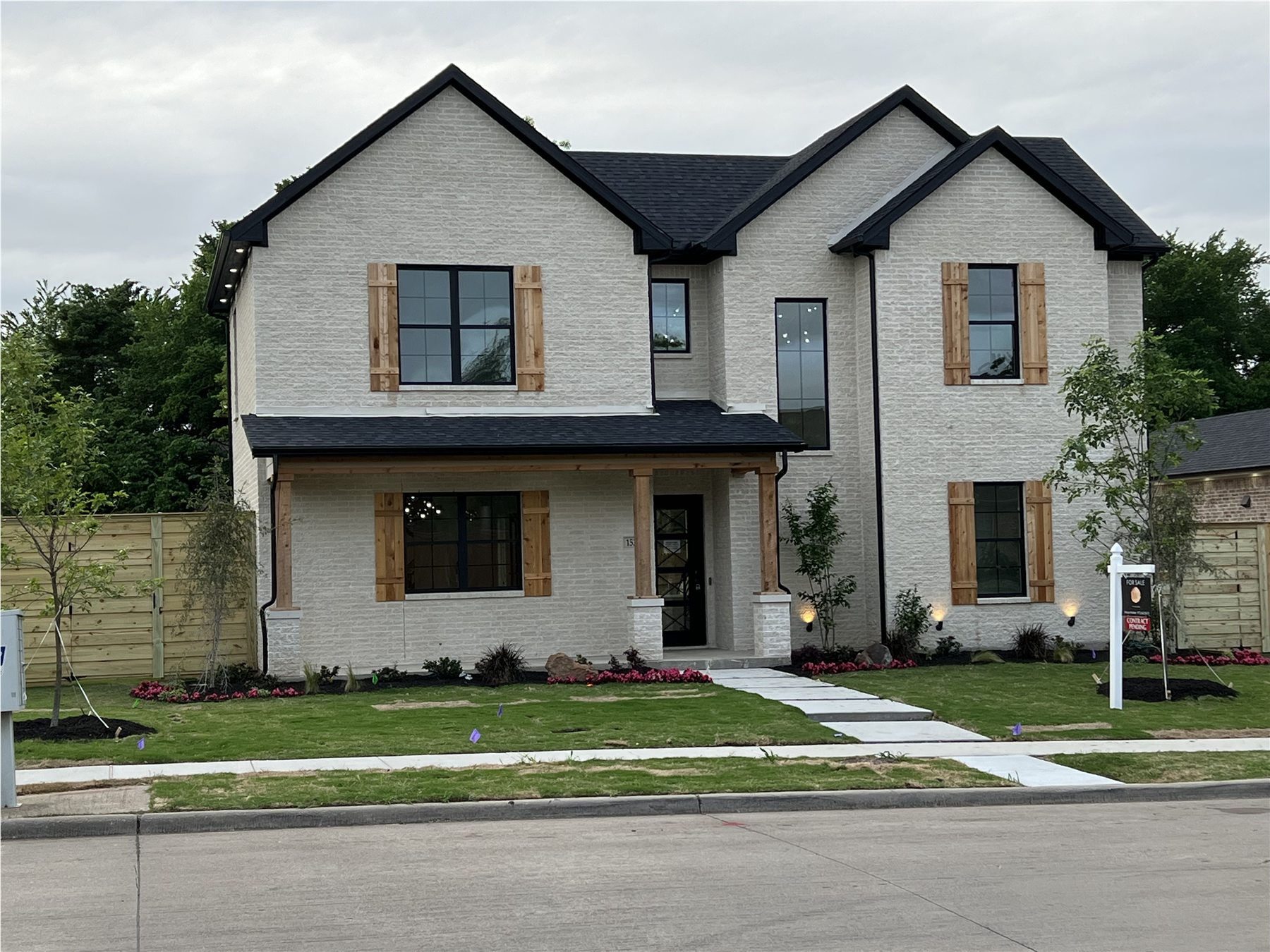 Two-story white brick home with black windows and wood shutters